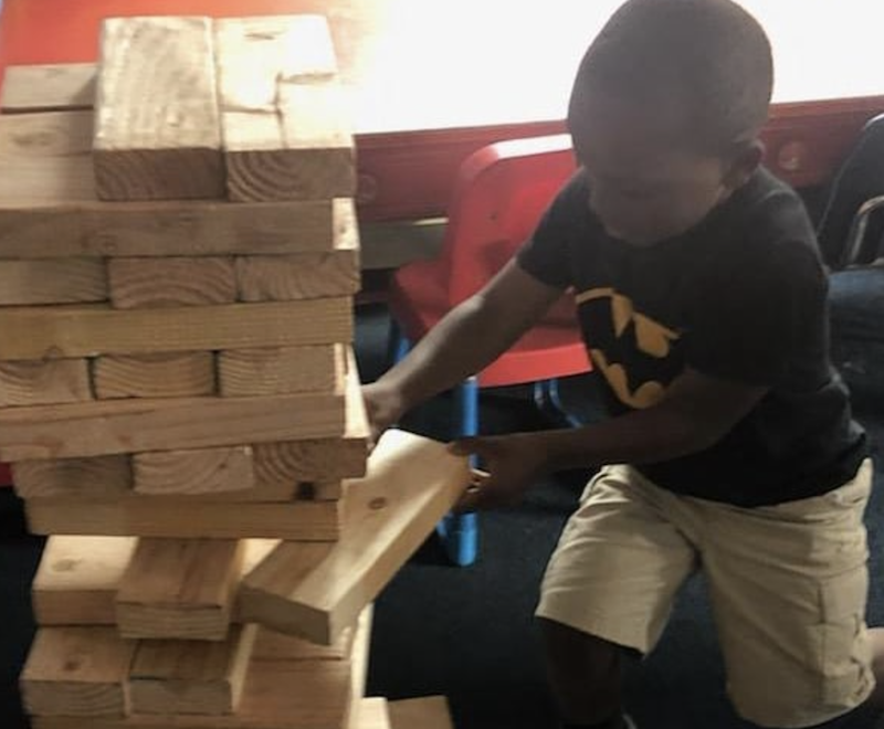 A boy is pulling a block from a super-sized Jenga block set.