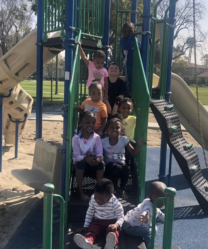 Kids are smiling for a picture sitting on the stairs at the jungle gym.