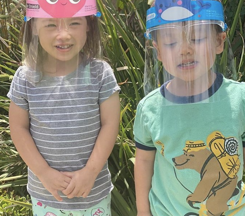 Girl and boy are wearing face shields to be safe from Covid are posing for a picture.