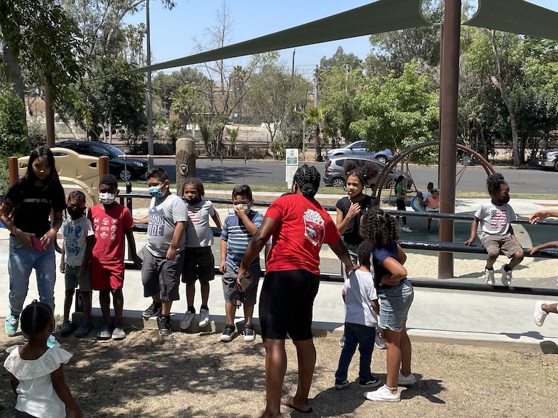 Kids are at the park lining up to play a game.