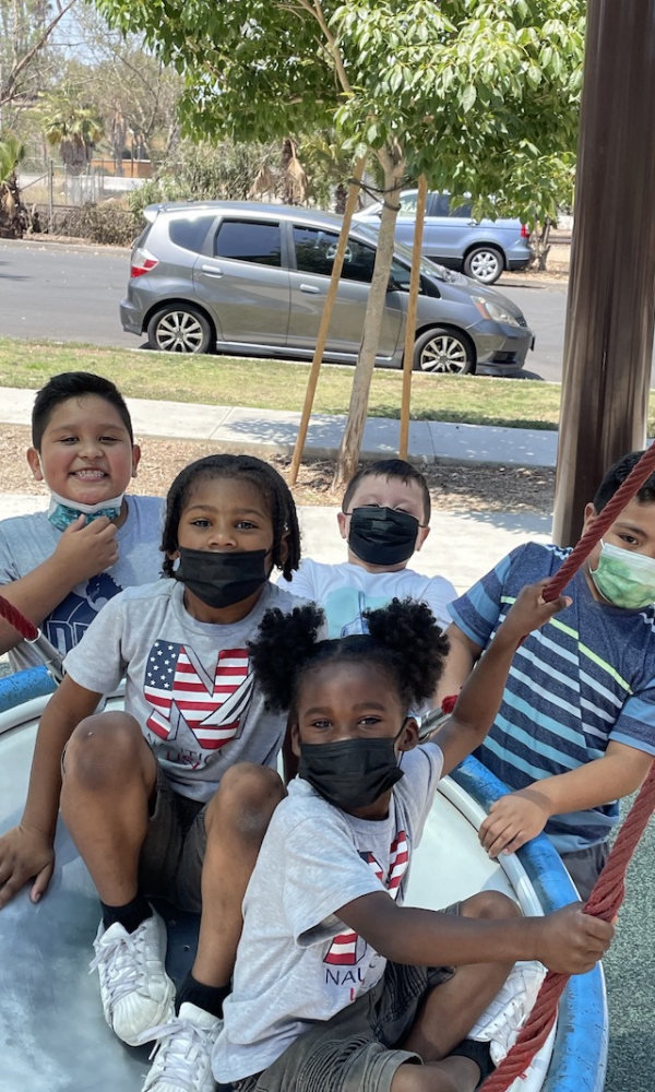 Children with face masks on are posing for the camera to take a picture.